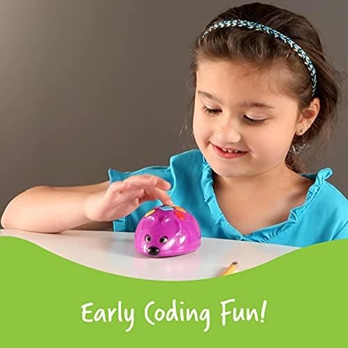Child pressing the directional buttons on the Code and Go Robot Mouse at a table