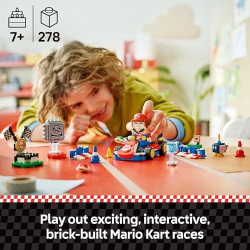 Young child playing an interactive brick-built LEGO Mario Kart race on a table, with the set marked ages 7 plus and 278 pieces