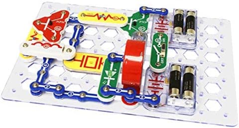 Snap Circuits colour-coded snap-together electronic components including snap wires, switches and a speaker on the clear grid baseplate